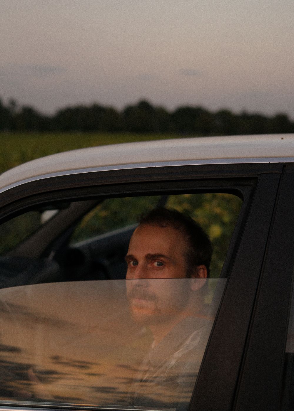 Piotr Kurek seen through a car window at dusk