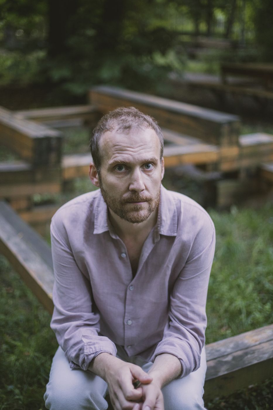 Piotr Kurek seated outdoors among wooden benches